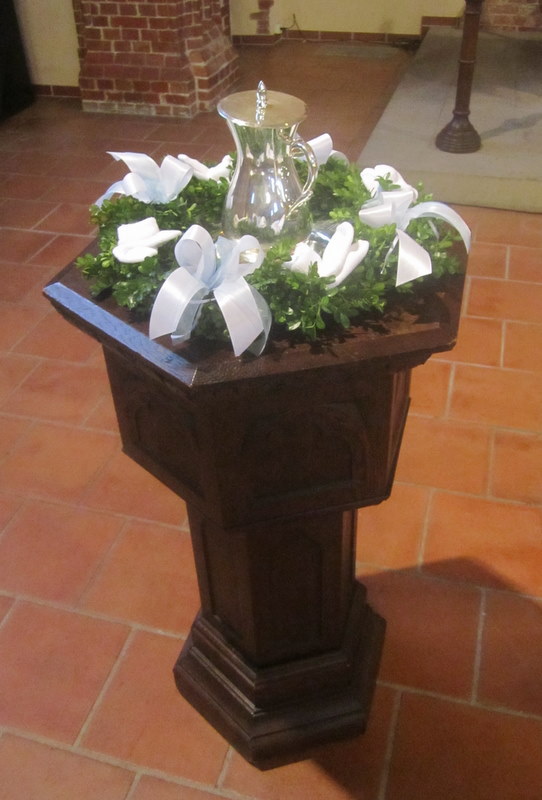 Geschmückter Taufstein der Matthäuskirche mit silberner Wasserkanne